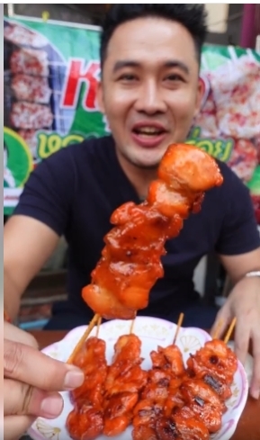 ผู้ชายถือไก่เสียบไม้ซอสแดง