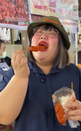 ผู้หญิงกำลังชิมไก่เสียบไม้