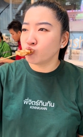 ผู้หญิงกำลังชิมอาหารเสียบไม้
